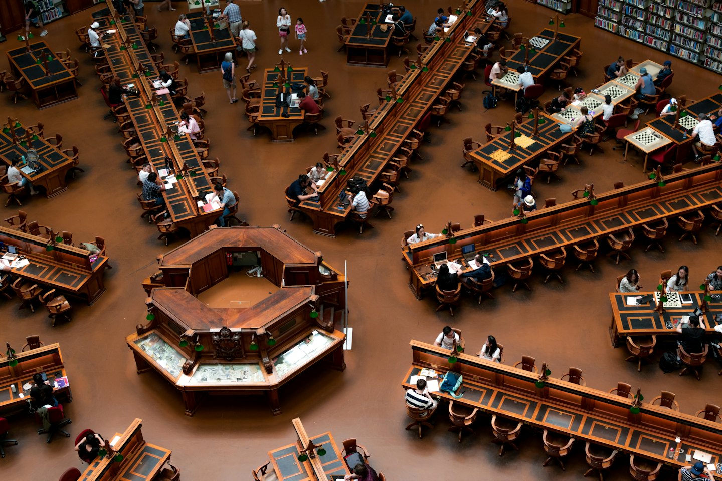 Ludzie uczący się i czytający w dużej czytelni bibliotecznej.