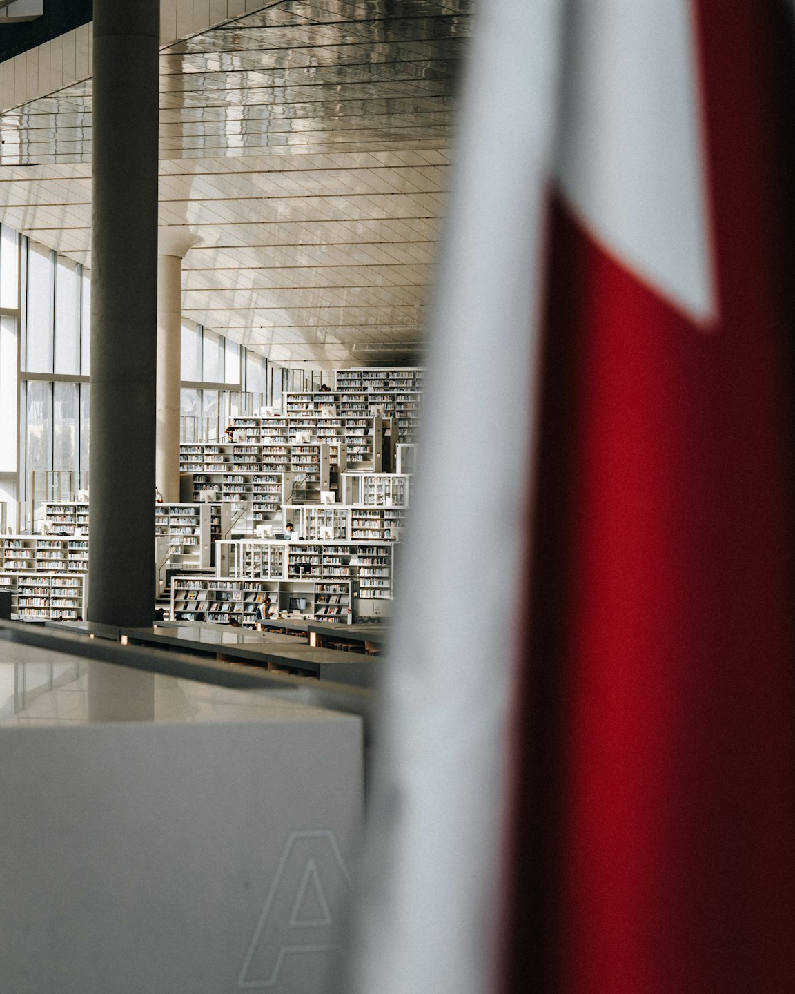 Ludzie przeglądają półki w przestronnej, nowoczesnej bibliotece.