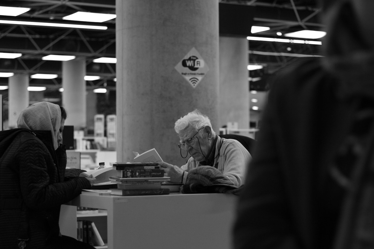 Dwie osoby czytają książki przy stole w bibliotece.