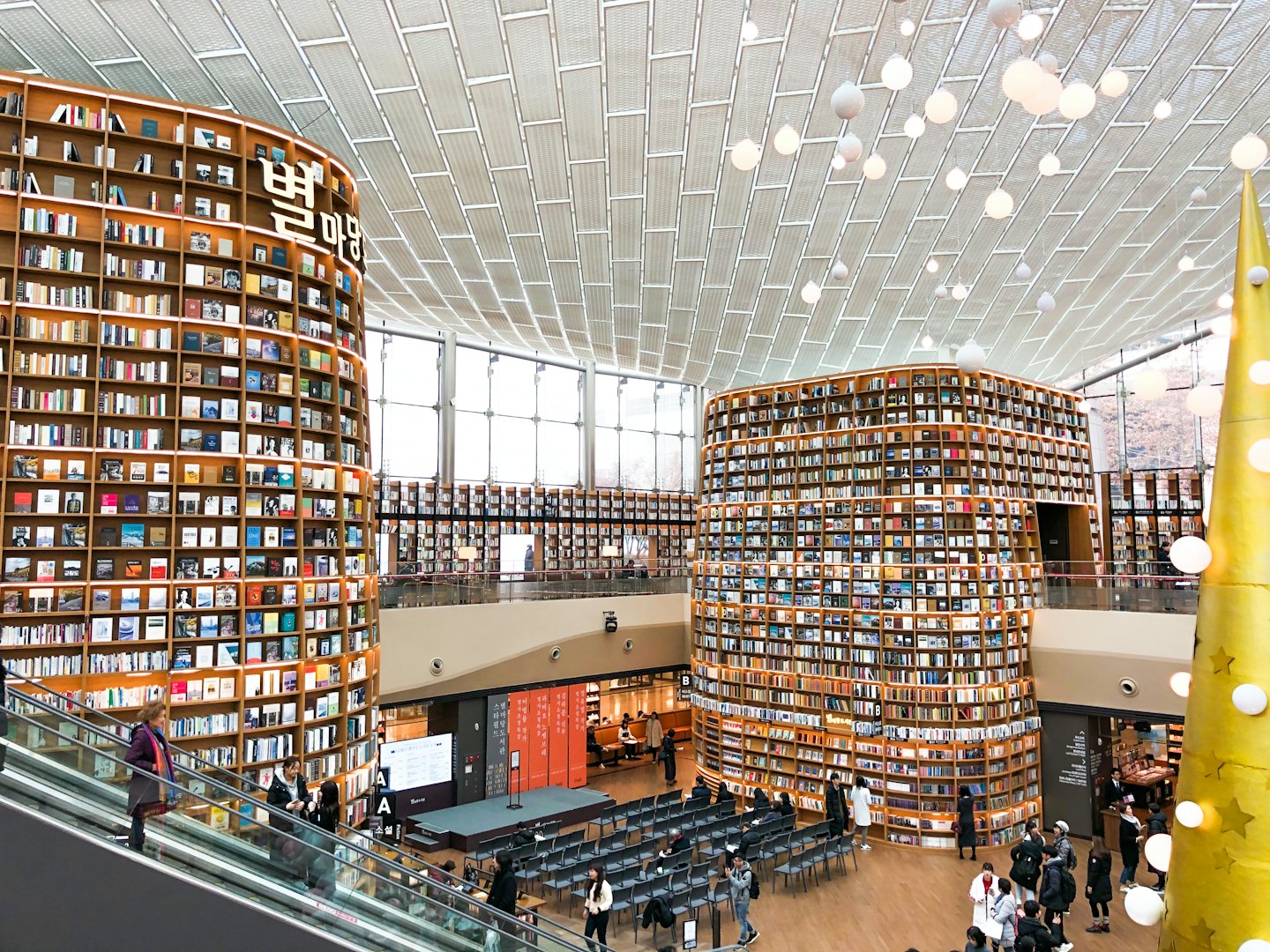 Klienci przeglądają książki w nowoczesnej bibliotece z drewnianymi regałami.