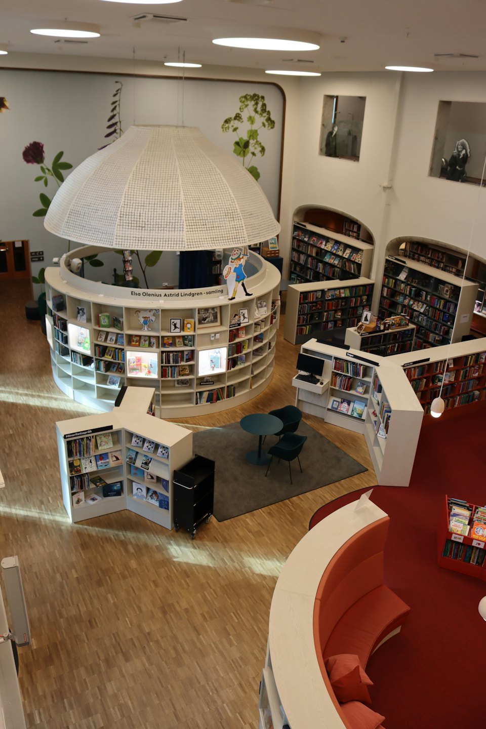 Nowoczesne wnętrze biblioteki z okrągłymi ekspozycjami książek i kącikami do czytania.